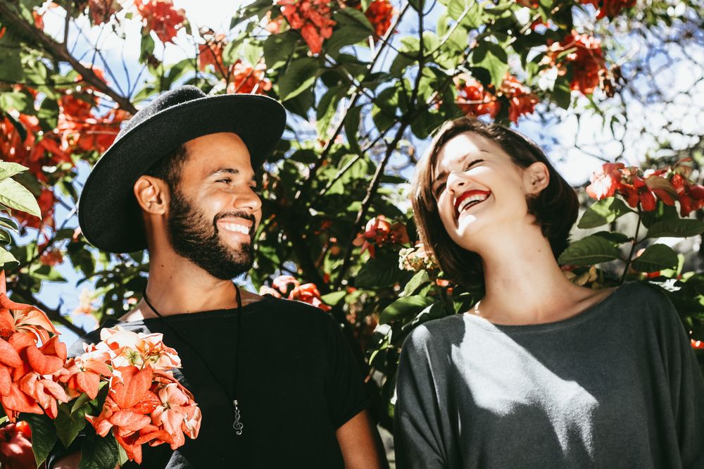 A smiling couple outdoors with trees in background