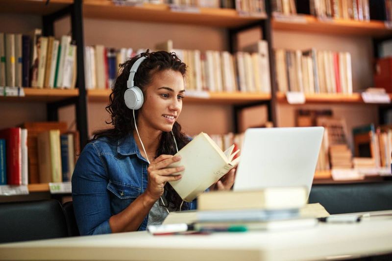 Girl studying in a library wearing headphones