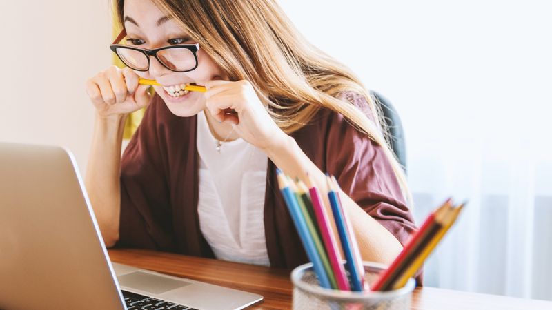 Nervous woman looking at laptop and biting a pencil | Canada visa refusal