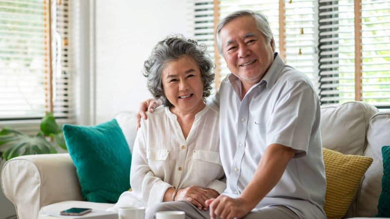 happy smiling Asian grandparents on couch | Parents and Grandparent Sponsorship Program Canada